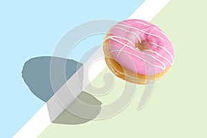 Creative disposition of pink donut on bright background. photo