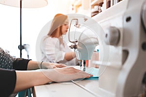 Creative dressmaker woman working with cloth on sewing machine. Two seamstress in design bureau making new clothing concept. Small