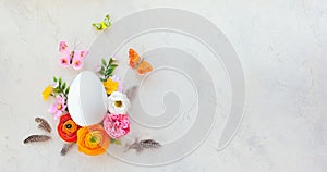 Creative Easter concept made of white egg butterfly and spring flowers around on vintage background. Flat lay