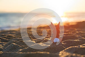 Creative easter concept photo of red paper bunny on the sand on the beach at sunset. Concept.