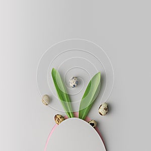 Creative Easter layout with rabbit ears and eggs on a gray background