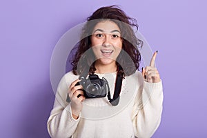 Creative energetic sweet lady raising her finger, opening her mouth and eyes widely, looking directly at camera, holding photo