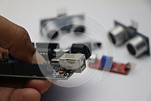 Creative engineer holding micro controller board which is programmable with various other kinds of sensors on background
