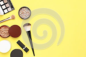 Creative Fashion background. Set of decorative cosmetics mascara powder lipstick eyeshadow blush makeup brush on yellow background