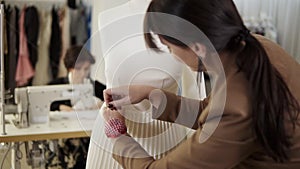 Creative fashion designers are working together in the tailor studio. Long haired woman pinning on the white skirt on