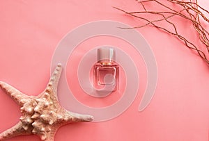 Creative fashion objects- women`s perfume and coral starfish on pink background. Top view, flat lay