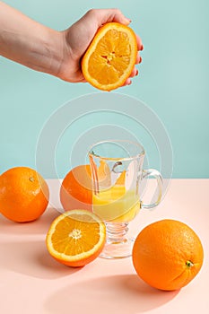 Creative and fashionable photo, pastel colors. Female hand crushes orange, juice.
