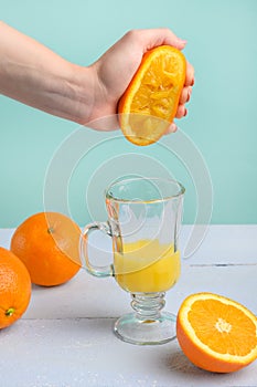 Creative and fashionable photo, pastel colors. Female hand crushes orange, juice. Vertical frame. Delicious juice and strawberry