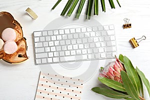 Creative flat lay composition with tropical flower, macaroons and computer keyboard