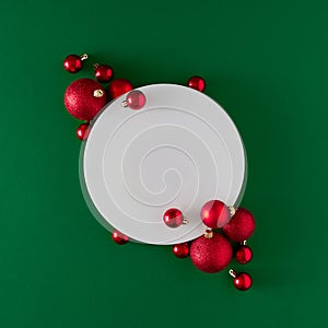 Creative flat lay holiday background made with Christmas baubles and frame on green background.