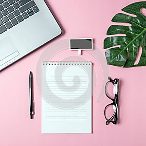 Creative flat lay photo of workspace desk with laptop, eyeglasses, palm leaf and notebook with copy space background.