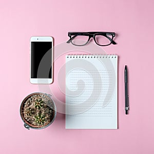 Creative flat lay photo of workspace desk with smartphone, eyeglasses, cactus and notebook with copy space background.