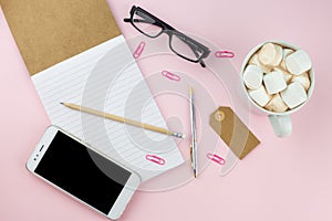 Creative flat lay photo of workspace desk with smartphone, eyeglasses, pen, pencil and notebook, minimal style on pink background.