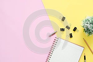 Top view office desk with open mock up notebooks and pencil and plant on pink yellow pastel color background.