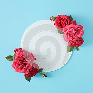 Creative flat lay with spring flowers and white frame on pastel blue background.