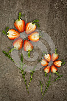 Creative flowers made of strawberries cut from below lit on a stone background Food concept