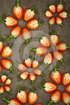 Creative flowers made of strawberries cut from below lit on a stone background Food concept