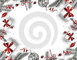 Creative frame made of Christmas fir branches, gift boxes, red decoration, sparkles and confetti on white background. Xmas