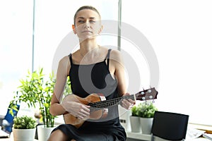 Creative girl in a black dress plays the guitar