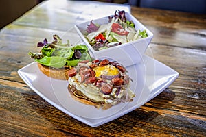 Creative, gourmet sandwich / salad combination plate with sausage, fried egg, cheese, and fresh greens.