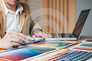 Creative graphic designer using graphics tablet to choosing color swatch samples chart for selection coloring with work tools and