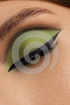 Creative green eye makeup with arrow. Beautiful macro shot of female eye make-up. Blue eye. Creative make-up. Perfect shape make-u