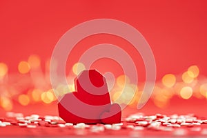 Creative greeting card for Saint Valentine day. Two big and small red hearts on red background with festive bokeh