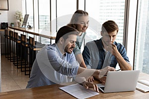 Creative group working in office together, sharing laptop