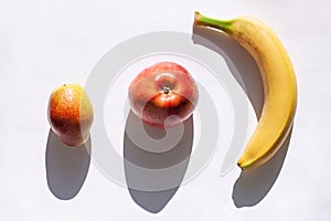 Creative healthy breakfast concept on a white background flat lay. Fresh banana, apple, pear fruits with natural shadow