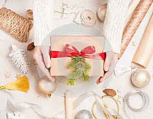 Creative hobby. Woman`s hands wrap christmas holiday handmade present in craft paper with twine ribbon. Making bow at xmas gift b