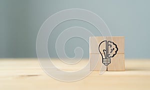 Creative idea concept. The wooden cubes with icon; a half of light bulb and brain isolated on grey background with copy space. Sym