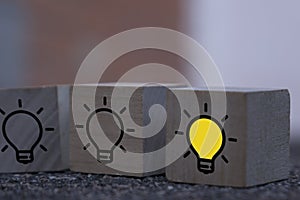 Creative idea, New idea, innovation and solution concept. wooden cubes with the yellow light bulb symbol on table, blue background