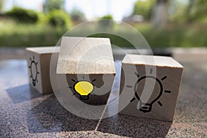 Creative idea, New idea, innovation and solution concept. wooden cubes with the yellow light bulb symbol on table, blue background