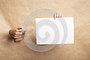 Creative idea. Woman pointing finger at empty sheet through torn brown paper, blank space for design