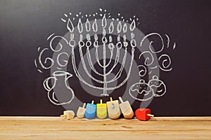 Creative Jewish holiday Hanukkah background with spinning top dreidel over chalkboard with hand drawing