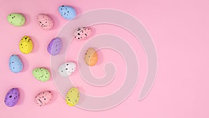 Creative layout with colorful eggs on pastel pink background. Sunlit Easter arragement. Flat lay concept copy space