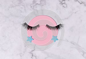 Creative layout with eyelashes. Closed eyes on marble background