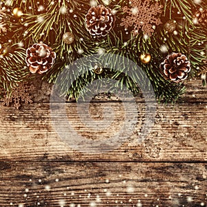 Creative layout frame made of Christmas fir branches, pine cones and gold decoration on wooden background.