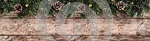 Creative layout frame made of Christmas fir branches, pine cones and gold decoration on wooden background.