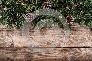 Creative layout frame made of Christmas fir branches, pine cones and gold decoration on wooden background. Xmas and New Year theme