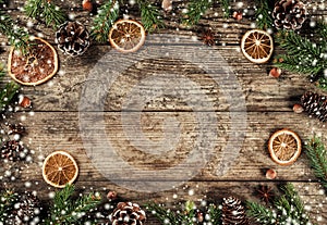 Creative layout frame made of Christmas fir branches, spruce, slices of orange, pine cones, snowflakes on wooden background