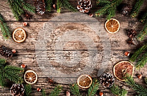 Creative layout frame made of Christmas fir branches, spruce, slices of orange, pine cones, snowflakes on wooden background