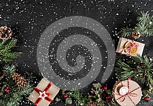 Creative layout frame made of Christmas tree branches, gifts, berries, pine cones on dark background with snowflakes
