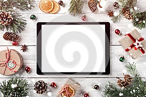 Creative layout frame made of Christmas tree branches, pine cones and tablet pc on white wooden background. Xmas and New Year