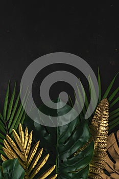 Creative layout with gold and green tropical palm leaves on black background. Minimal summer abstract pattern