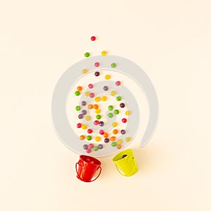 Creative layout of green and red buket with colorful candies. White aesthetic.