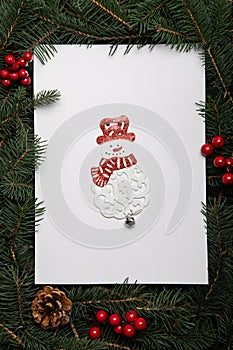 Creative layout made of Christmas tree branches with paper card note and Snowman ornament. Nature New Year concept