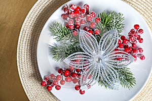 Creative layout made of Christmas tree branches with red berries served on a white plate