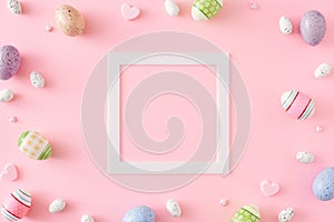 Creative layout made of colorful eggs, hearts on pastel pink background and frame