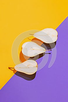 Creative layout made of raw sliced pears on bright violet and orange geometric background with shadow. Minimal style. Healthy food